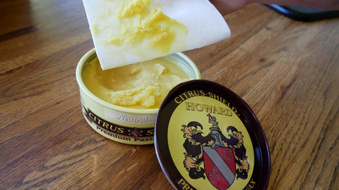 Open tin of Citrus Shield Paste Wax For Wood Furniture Polish And Cleaner Final Finish 11 Ounce Neutral with lid on wood surface.