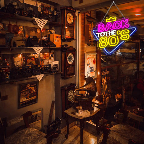 Vintage cafe setting with 'Back to the 80s' neon sign in bright colors illuminating retro decor and furniture.