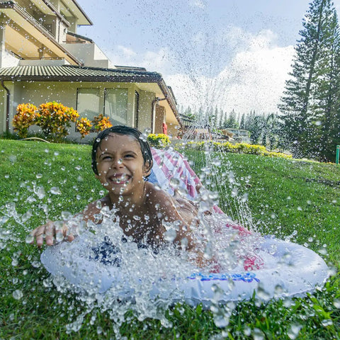 Child playing on Stars And Stripes Kids Inflatable Backyard Water Slide With Built In Splash Pool Over 14 Feet Long Quick Setup In Under A Minute Connects To Standard Garden Hose Blue Backyard Summer Fun For Active Kids in garden area.