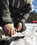 Person securing ice shelter with Self Tapping Ice Shelter Anchors Stainless Steel Screw In Two Pack For Windy Days Keeps Your Ice Shelter In Place With Easy Grip And Durable Construction on snowy ground.