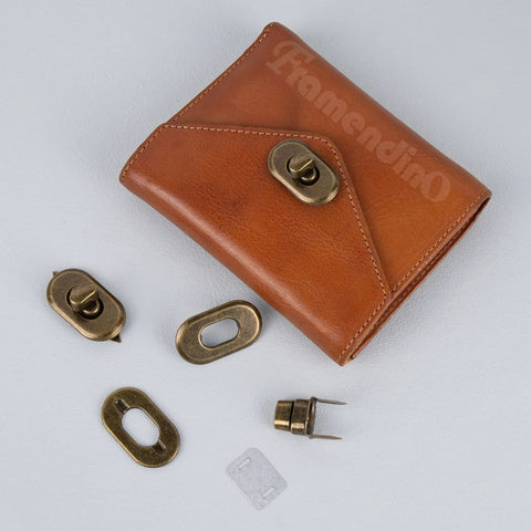Brass turn-lock purse hardware set; includes multiple plates and fasteners on brown leather wallet display