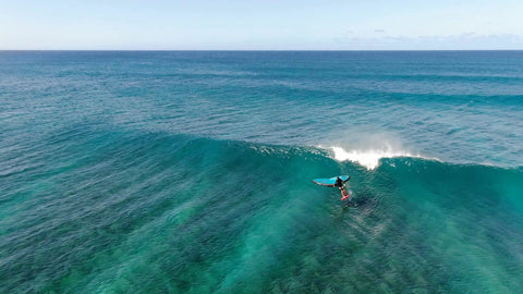 Person surfing with Alien Wing 6M High Performance Wind Wing For Foiling And Surfing Lightweight Aerodynamic Rigid Wing Includes Backpack Wrist Leash And Repair Kit Tri Color on ocean wave