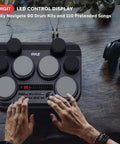 Person playing Compact Tabletop Electronic Drum Pad Kit With 8 Touch Sensitive Pads And Pedals, 600 Sounds on wooden surface.