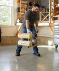 Man lifting a 2 HP Portable Twin Stack Air Compressor Powers Through Tough Jobs With Amped Up 3.2 CFM Performance in garage.
