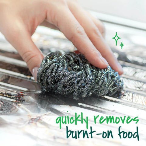 Hand using three pack stainless steel dish scrubbers that power through tough grease and burnt on messes on a metal surface