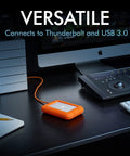 Rugged USB C 4TB Portable External Drive With Drop, Shock, Dust And Rain Resistance for Mac and PC on a desktop setup with accessories