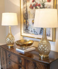 Set of 2 Fletcher Glass Genie Table Lamps in Ombra Gold Mercury Glass With White Lamp Shades placed on wooden console
