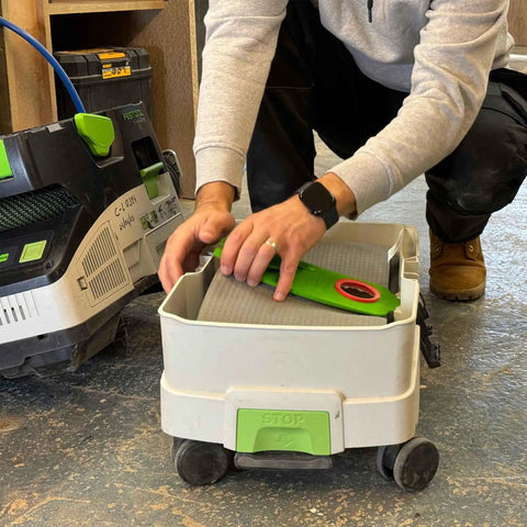 Person placing reusable dust bag for Festool Midi CT 15 E and CT 25 HEPA extractors into vacuum part on shop floor.