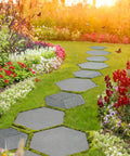 Two-Size Hexagon Stepping Stone Molds for Concrete installed in a garden path among colorful flowers and green grass.