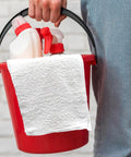 Person holding a red bucket with cleaning spray bottles and a white Bar Mop Towels Value Pack Of 60, 14 By 17 Inches, Absorbent And Durable Multipurpose Cleaning Rags, Cotton Terry Cloth Towels, Reusable Shop Rags, White, Eco Friendly And Made From Recycled Cotton For Everyday Cleanup draped over the edge.