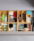 Bamboo Drawer Organizer Set Of 9 For Kitchen And Office, Crushes Junk Drawer Chaos While Keeping Cutlery Silverware Utensils Makeup And Desk Supplies Neatly Sorted In Bathrooms And More; drawer with various organized items like cosmetics.