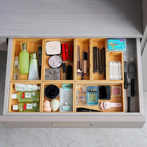 Bamboo Drawer Organizer Set Of 9 For Kitchen And Office, Crushes Junk Drawer Chaos While Keeping Cutlery Silverware Utensils Makeup And Desk Supplies Neatly Sorted In Bathrooms And More; drawer with various organized items like cosmetics.