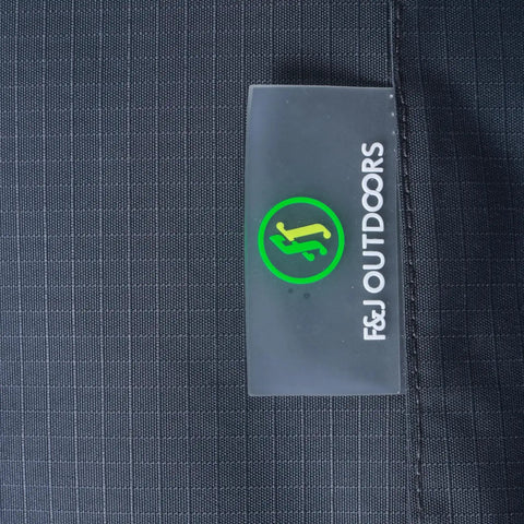 Close-up of Heavy Duty Waterproof Rectangular Patio Table Cover 86 by 44 by 27.5 Inches, showing gray ripstop fabric and logo tag.