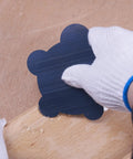 Gloved hand using nine piece cabinet scraper set for woodworking with burnisher, rectangle scrapers, curved, gooseneck, edges on wood