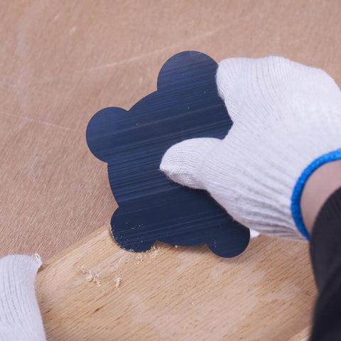 Gloved hand using nine piece cabinet scraper set for woodworking with burnisher, rectangle scrapers, curved, gooseneck, edges on wood