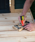 Loctite PL Premium polyurethane construction adhesive tube (4 oz) being squeezed onto wooden letters on a deck