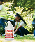 Heavy Duty Industrial Strength Vinegar Concentrate With Eighty Percent Acetic Acid For Tough Cleaning At Home And Outdoor Jobs Dilutes Easily Technical Grade Safe For Septic Systems 128 Ounce Bottle shown in a garden setting with a person cleaning nearby.