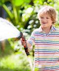Child watering garden with hose, demonstrating Garden Hose Quick Connectors Three Quarters Inch Universal Fit With Quick Release Fittings Set Of Four Adapters Two Male And Two Female For Easy On And Off Watering Gear And Sprayers.