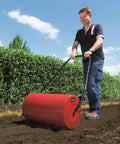 Person using GC GR 57 Garden Roller For Lawn And Grass Red Manual Push Roller With Coated Metal Drum Side Filler on soil