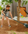 Woman using 18 Inch Manual Lawn Aerator With Heavy Duty Rolling Tines And 27 Rustproof Spikes, 51 Inch Detachable Handle around a tree.