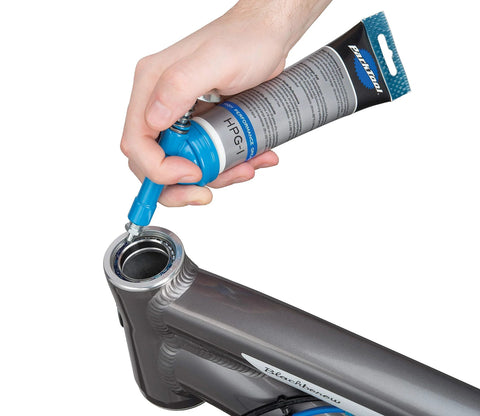 Park Tool GG-1 Fat Press, silver; side view of hand using blue press to install into bicycle head tube.