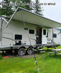 RV Awning Tie Down Kit With Shock Absorbing Springs And 13ft Ratchet Straps securing an awning on a camper in a grassy area