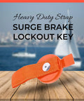 Orange surge brake lockout key with heavy-duty strap, front view on wooden deck