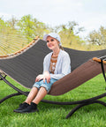 Person sitting on Portable Standing Patio Hammock With Foldable Steel Stand in dark gray on grass