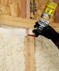 Premium Closed Cell Spray Foam Insulation Can With Wide Trigger Sprayer in hand applying spray into wall studs.