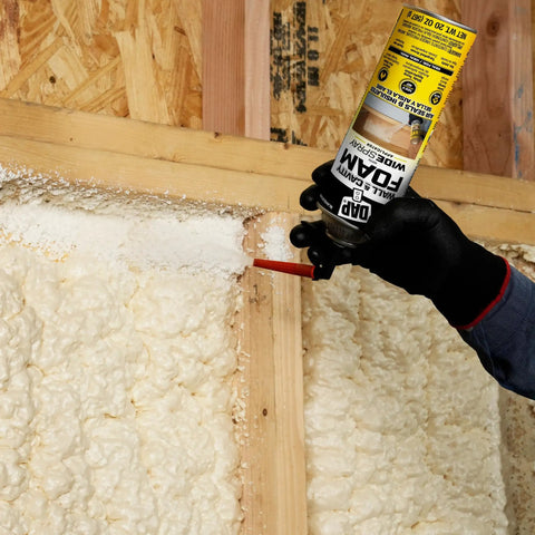 Premium Closed Cell Spray Foam Insulation Can With Wide Trigger Sprayer in hand applying spray into wall studs.