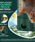 Heavy Duty Weight Activated Squirrel Proof Bird Feeder For Outdoor Hanging Large Capacity All Metal Weatherproof And Durable No Fuss Four Perches Attracts Finches Cardinals Blue Jays Chickadees Green shown deterring a squirrel