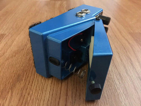 Harmonist Guitar Pedal PS-6 with battery compartment open, showcasing blue finish and spring mechanism on wood surface.