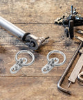 Rock Solid Stainless Steel Pad Eye Plates And Heavy Duty Mounting Rings With M5 Threads on a workbench beside tools.