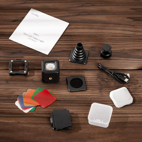 RM01 Mini LED Video Light Pro Grade On The Go Waterproof Portable Lighting Kit with 8 color filters and accessories on wooden surface.