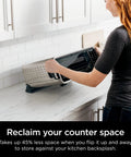 Woman storing Digital Air Fry Pro Countertop Oven With Extended Height And XL Capacity For Big Meals, Flip Up Storage Design on counter.