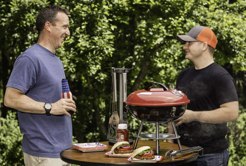 Two men using a 14 Inch Portable Charcoal Grill With Locking Lid And Dual Vents Lightweight Tabletop BBQ in a backyard