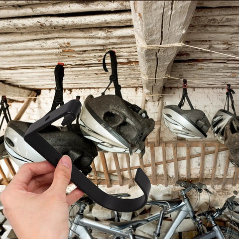 Four Pack Overhead Garage Storage Hooks Black Heavy Duty Ceiling And Wall Hanging Hooks For Garage Home Office Kitchen And Bathroom Organization No Tools Needed shown holding helmet.