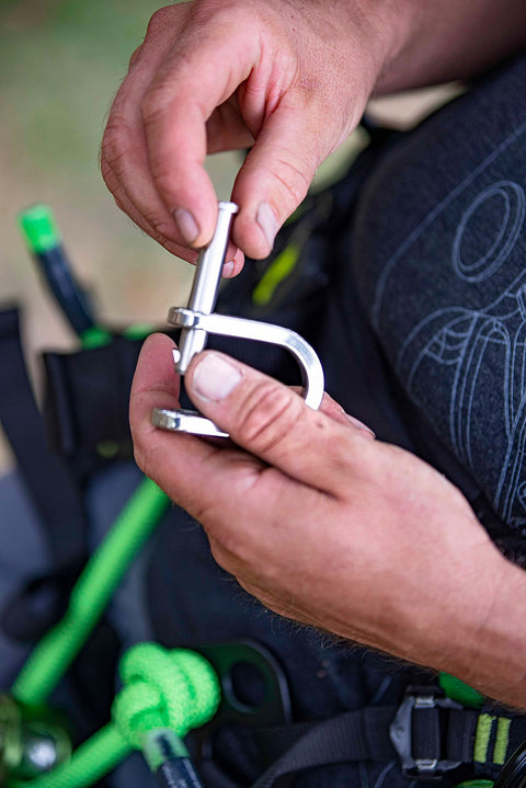 Hands using V3 Quickie Steel Shackle For Basal Canopy Anchors Or Redirects With Quadruple Action Rotating Slic Pin in outdoor setting