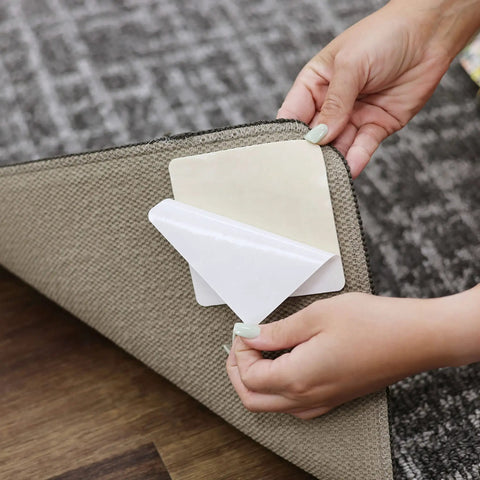 Person applying Non Slip Corner Gripper Rug Tabs Eight Pack Anti Curling Double Sided Adhesive 4 Inch By 4 Inch Squares to rug corner