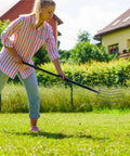 Person using Heavy Duty Versatile Manure Fork With Solid Design For Outdoor Farming And Gardening in a grassy backyard area.