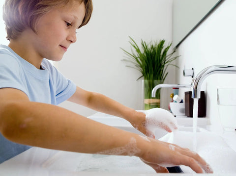 Child washing hands in a sink, demonstrating use of Electric Mini-Tank Water Heater Tronic 3000 T 2.5 Gallon ES2.5 Hot Water On Tap