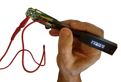 Hand holding a Shielded Two Wire Probe Connector For LCR Reader And Smart Tweezers ESR Meters with PCB component