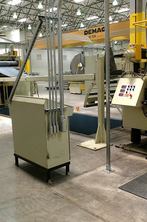 Industrial factory setting with machinery, control panels, and ceiling cranes visible, no specific products shown.