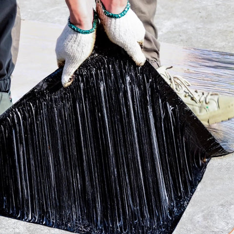 Hands holding Straight Up Heavy Duty Self Adhesive Roofing Membrane with a solid waterproof seal, ready for application.