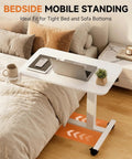 Adjustable Pneumatic Standing Desk On Wheels With Lockable Casters Mobile Laptop Desk Overbed Bedside Table For Home Office 28 Inch Wide By 16 Inch Deep White placed over a bed with laptop and mug.