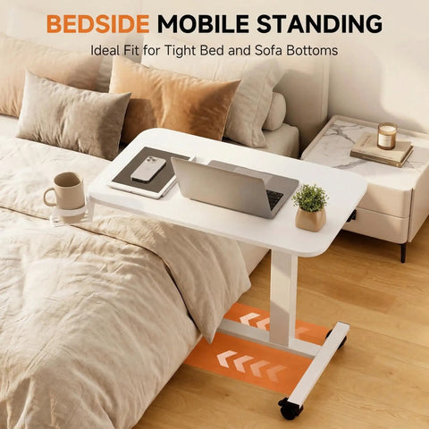 Adjustable Pneumatic Standing Desk On Wheels With Lockable Casters Mobile Laptop Desk Overbed Bedside Table For Home Office 28 Inch Wide By 16 Inch Deep White placed over a bed with laptop and mug.