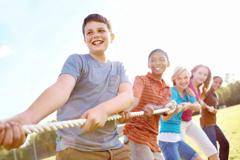 Group of children playing tug of war with a rope outdoors