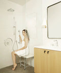 Woman in bathroom using 18 Inch Decorative Oval Wall Mount Grab Bar With Concealed Flanges For ADA Safety And Solid Grip 1.5 Inch Diameter