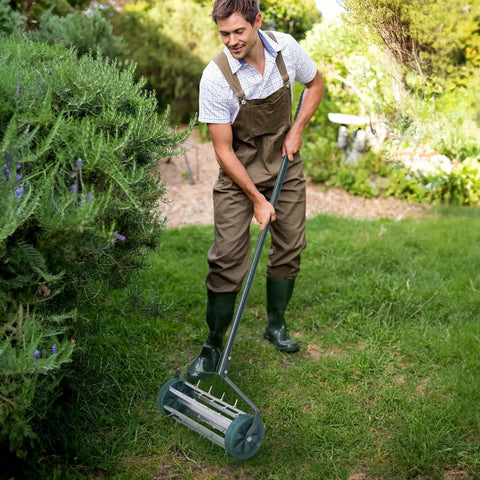 Man using 17 Inch Heavy Duty Rolling Lawn Aerator with sharp spikes and anti-slip handle on garden lawn for manual aeration tool.