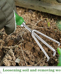 Hand using Three Tine Claw Garden Rake With Ergonomic Handle And Stainless Steel Build for loosening soil and weeding in garden